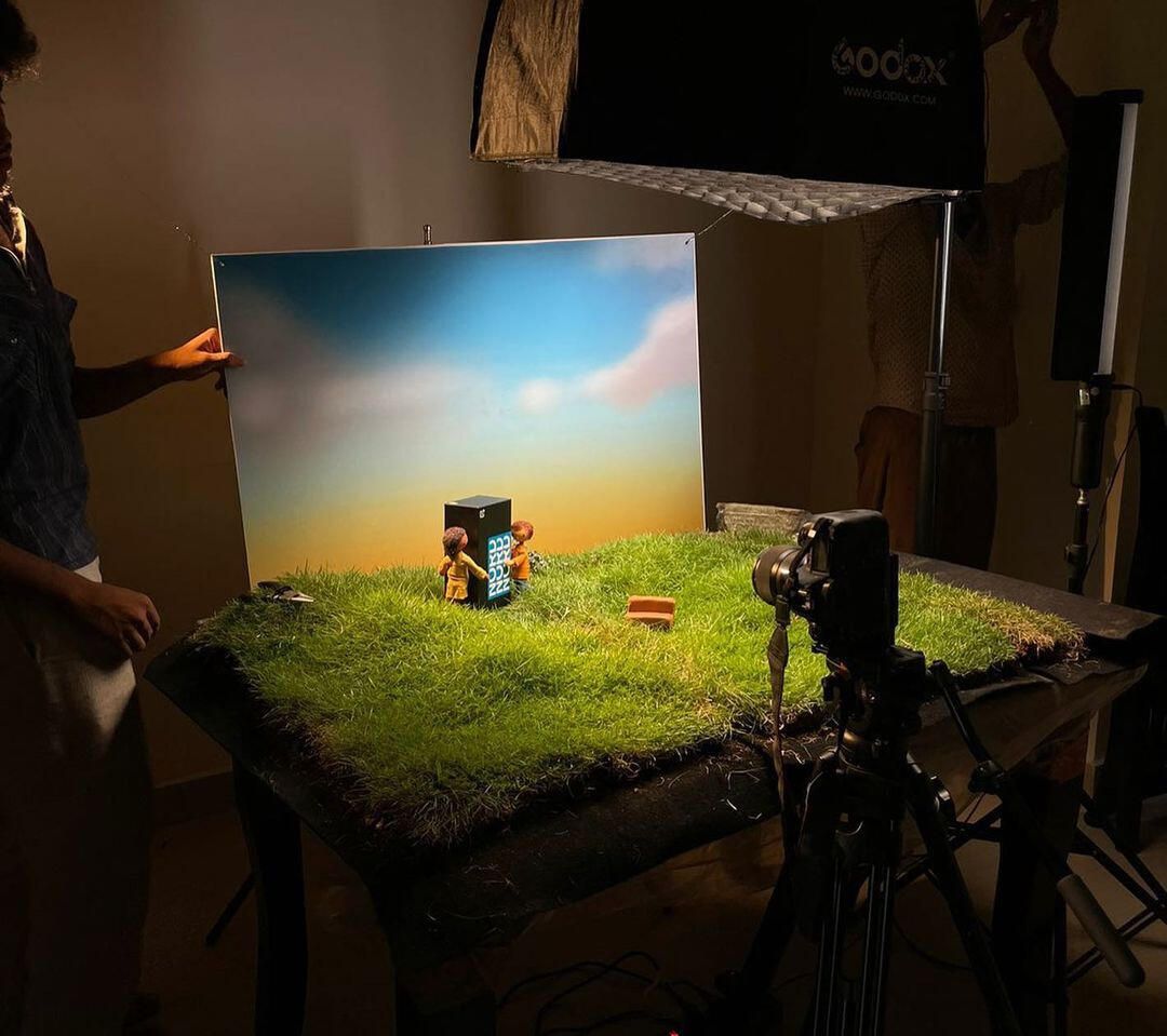 Camera on a tripod facing the lit miniature set