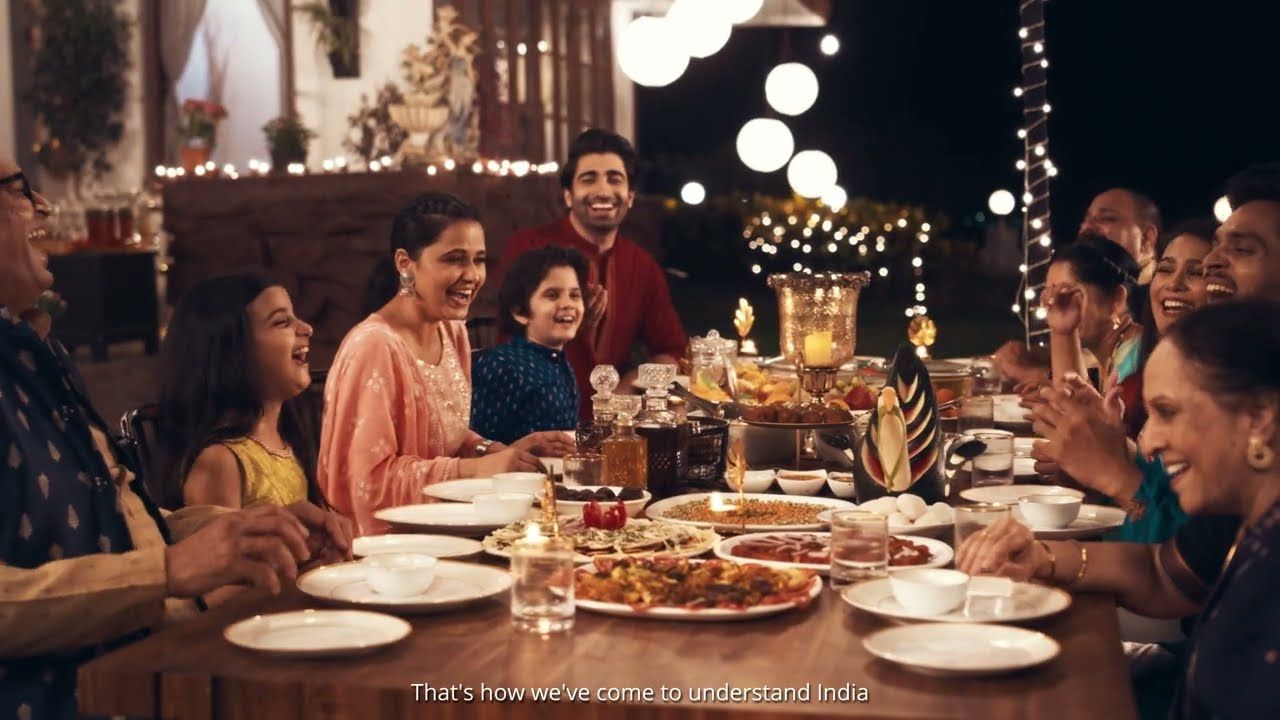 A long, warmly lit dinner table, from the SATS launch film