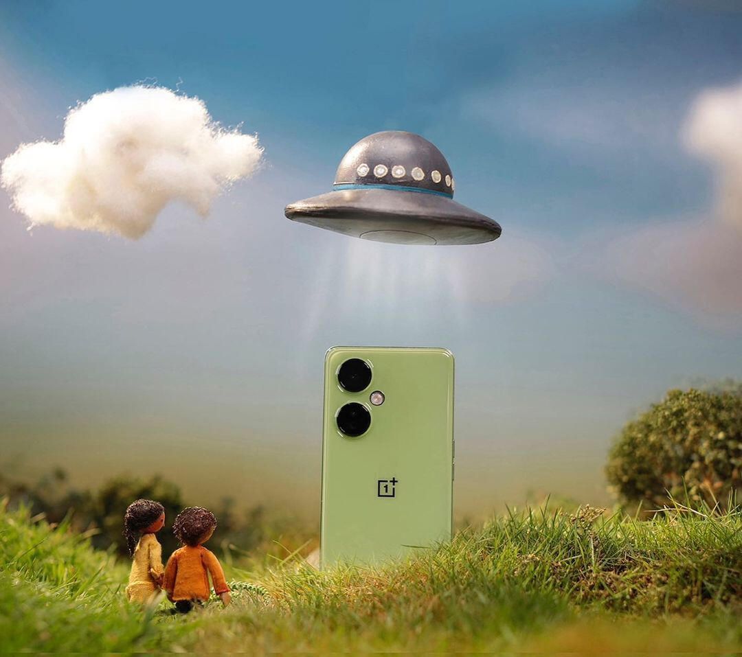 A UFO beams down a green phone on a miniature hill