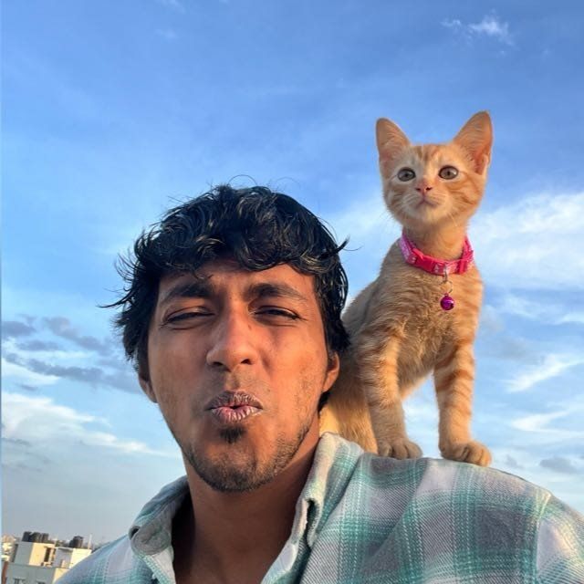 Gino George on a rooftop with an orange kitten on his shoulder