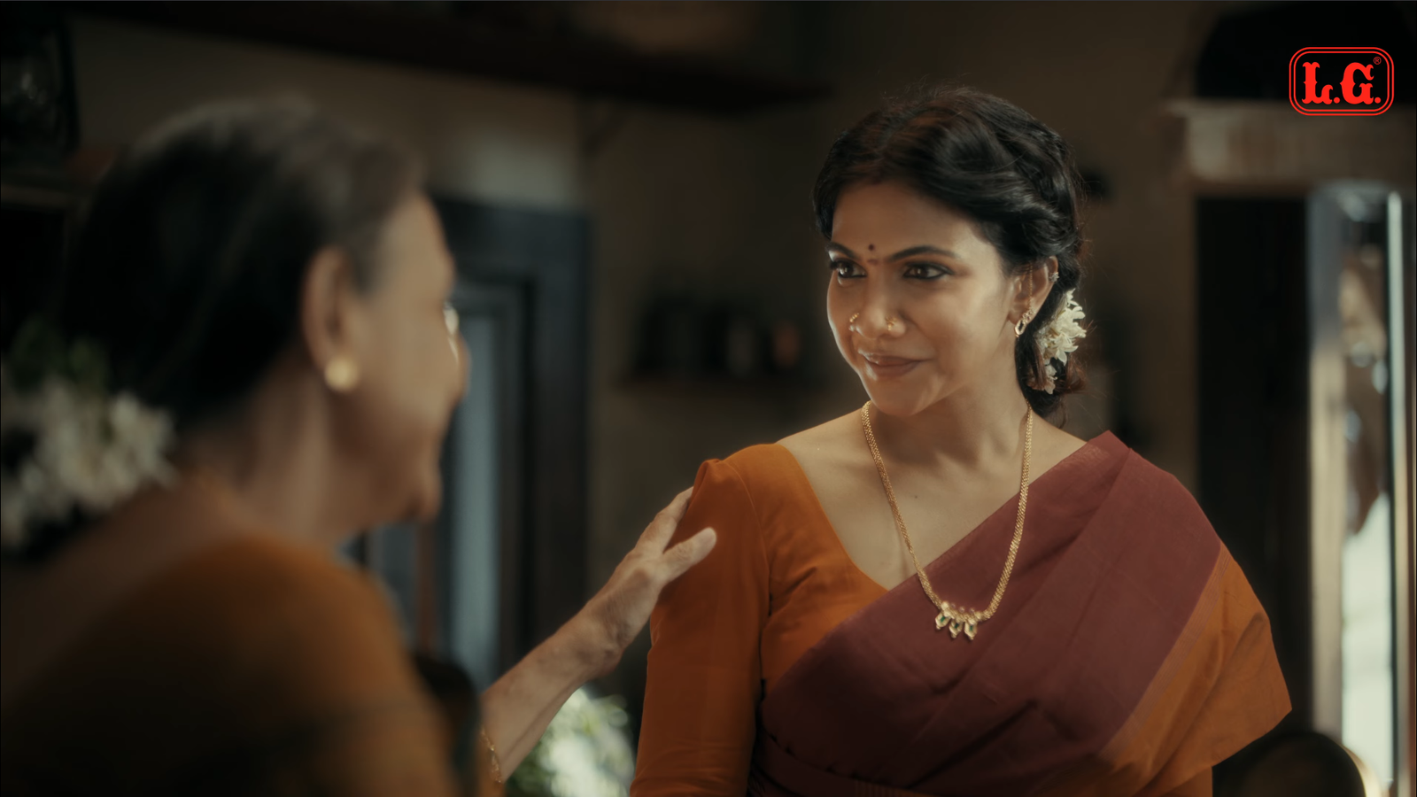 A woman in a yellow sari smiling in a kitchen, from the LG Hing commercial